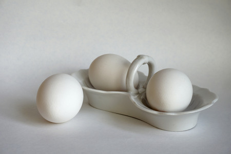 chicken eggs in white ceramic ware on white background in light colorsの写真素材