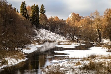 Autumn landscape with river and trees. The banks of the river are covered with snow.の写真素材