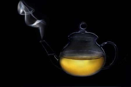 the subject of a transparent teapot with tea, from the spout there is steam, a light contourの写真素材