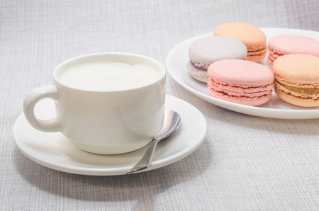 Cake macaroon on the plate and a frothy coffee, close upの写真素材
