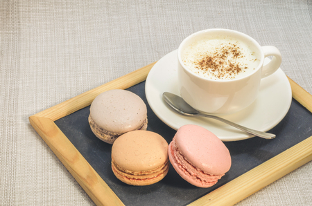 Cake macaroon on the plate,cinnamon and a frothy coffee close upの写真素材