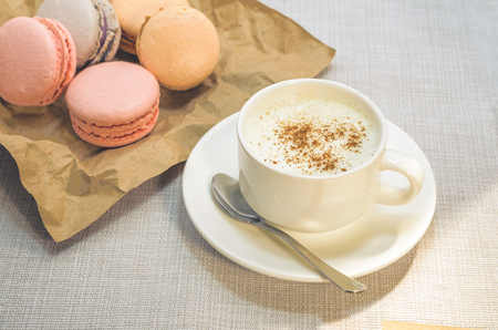 Cake macaroon on the plate,cinnamon and a frothy coffee close upの写真素材