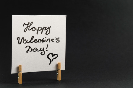 The sticker with the greeting happy Valentines day on the clothespin on a dark backgroundの写真素材