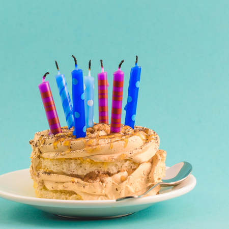 Chocolate cake with cream and lots of candles on a blue backgroundの写真素材
