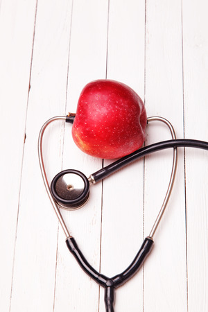Medical stethoscope and red apple on a white tableの写真素材