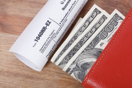 Money In Wallet and tax form with calculator on wooden table