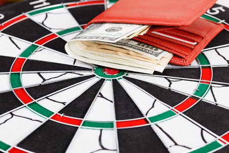 Close up view of red arrow and one hundred dollar bill on dart board.の写真素材