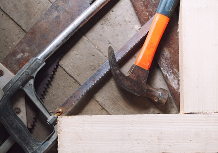 Hammer and saws lays on wooden floor