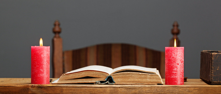 Open book and burning candles on the vintage wooden table.の写真素材