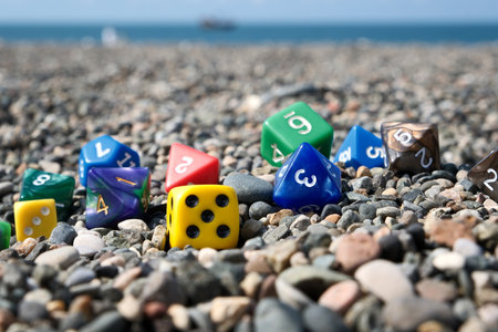Colorful dice on a pebble beach with the sea in the backgroundの写真素材