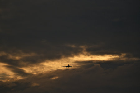 Silhouette of a plane flying in the sky at sunset.