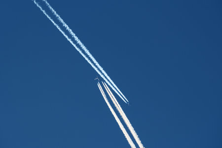 Airplane in the blue sky with contrail, closeup of photoの写真素材