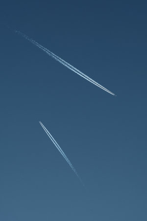 airplane trail in the blue sky with some contrail on it