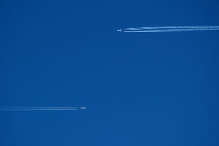 airplane in the blue sky with contrailの写真素材