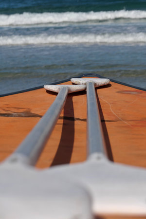 Close-up of a paddles and paddle board on the background of the sea. 2 paddles resting on the paddleboard. Wooden boat and two paddles on the sea in the summer.の写真素材
