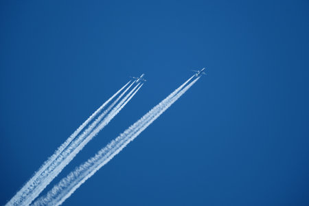 Airplanes in the blue sky with white contrail. Two contrails. Blue sky background.の写真素材