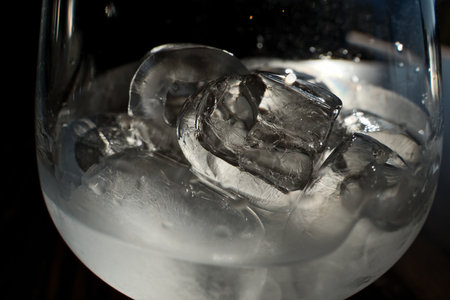 Ice cubes in a glass of water on a dark background. Close-up.の写真素材