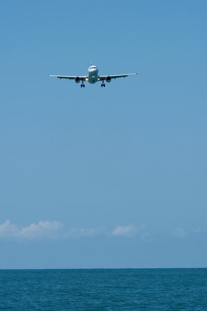Airplane in the blue sky on the background of the sea.