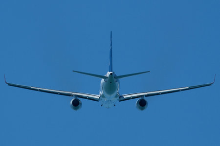 Airplane in the blue sky. An airplane moving away after takeoffの写真素材