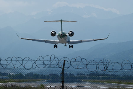 A commercial passenger jet approaches the runway for landing, captured from behind as it descends...