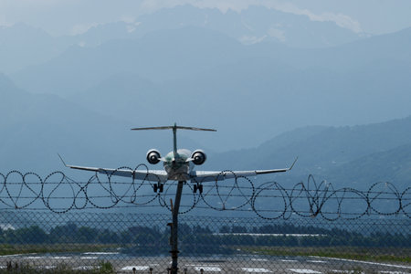 A commercial passenger jet approaches the runway for landing, captured from behind as it descends...