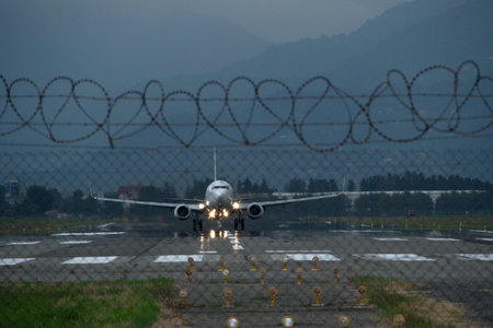 Airplane taking off from runway with barbed wire in the backgroundの写真素材