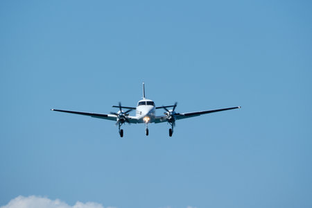 Small propeller plane flying in the blue sky on a sunny day. Twin-engine plane soaring through a...