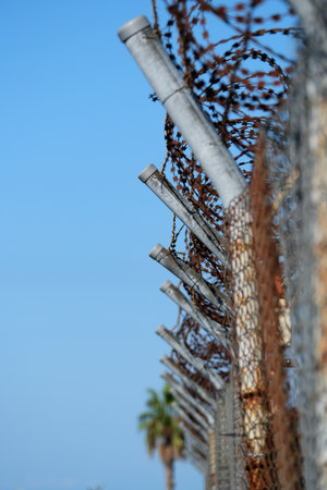 Fence with barbed wire against the blue sky. Selective focus.