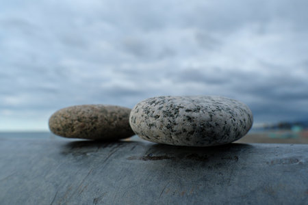 Two stones on the beach. Pebbles on a surface with a cloudy sky in the background