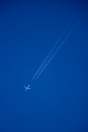 Airplane in the blue sky with white trace of a plane.