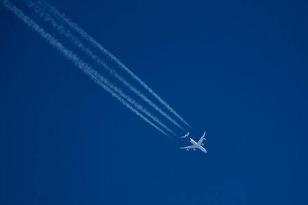 Airplane in the blue sky with contrails on a sunny day