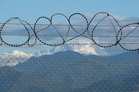 Barbed wire fence with snow capped mountains in the background. Selective focus.の写真素材