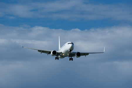 Airplane in the cloudy sky. The white plane prepares to land against a backdrop of clouds.