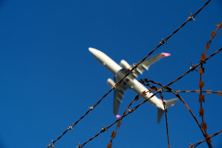 Airplane and barbed wire against the blue sky in the backgroundの写真素材