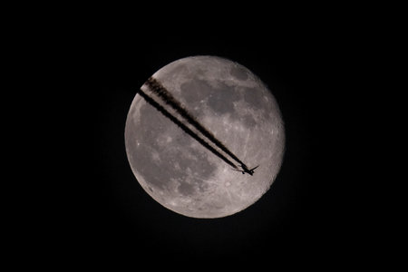 Airliner flying in the night sky with a full moon.の写真素材