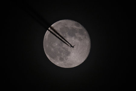 Aerial view of airplane flying over the full moon in the nightの写真素材