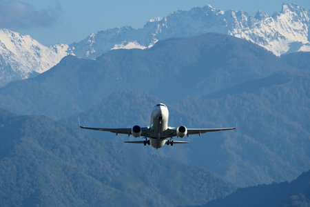 Rising plane against mountain backdrop. Plane Taking Off with Snow-Capped Mountains in Background