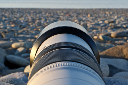 Close up of a camera lens on a stony beach at sunset