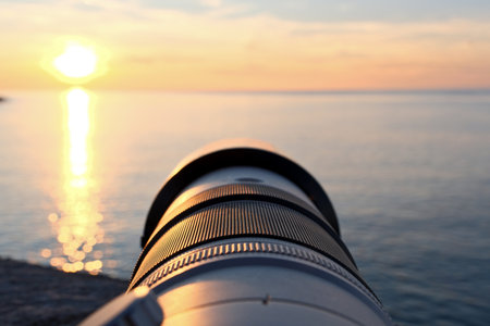 Camera lens on the background of the sea and the setting sun.の写真素材