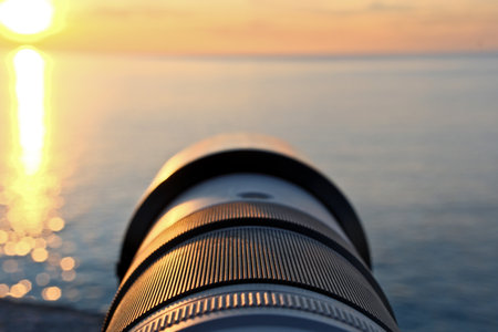 Camera lens on the background of the sea and the setting sun.の写真素材