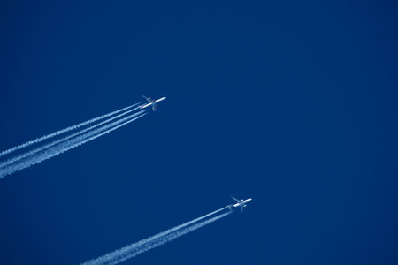 Airplanes in the blue sky. Contrails from two planes flying side by sideの写真素材