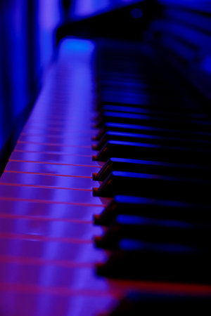 Piano Keyboard in Neon Blue Light, Close-Up with Bokeh Backgroundの写真素材