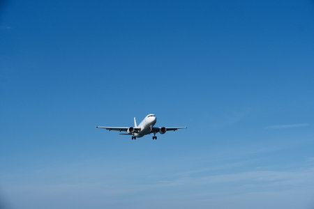 White Airplane Approaching for Landing Against Blue Sky and Clouds