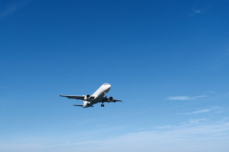 White Airplane Approaching for Landing Against Blue Sky and Clouds