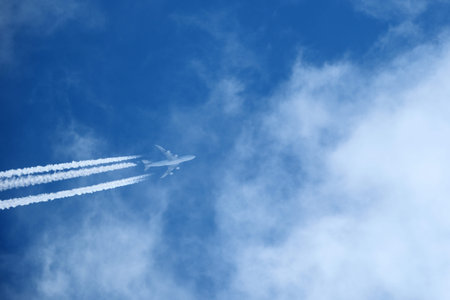 White airplane flying through dense clouds. Aircraft partially hidden in thick clouds and white mist