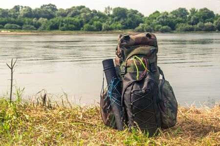 green camouflage tactical military backpack stands on the banks of the riverの素材 [FY310149868210]