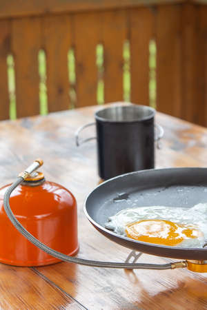 fried eggs in a skillet on a portable camping stove.の写真素材