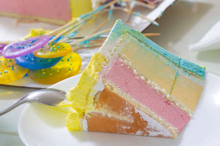 a cut piece of a multi-colored cake with a spoon and caramel next to it