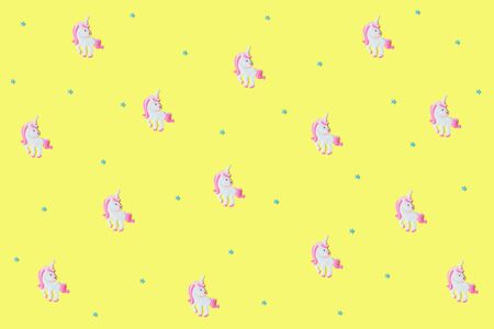 Pink unicorns with blue stars on yellow backdrop. Yellow background for your text. Festive concept. Flat lay style.の写真素材