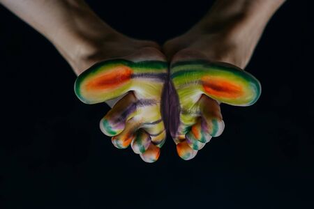 Bright multi-colored butterfly from toes. Black background. Art concept for medicine or cosmetology.の写真素材